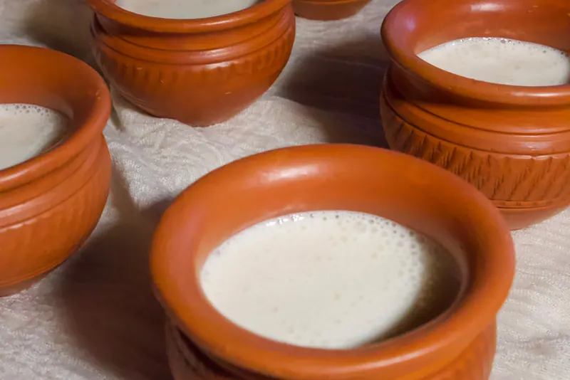 Terracotta clay pots of mishti doi on a cream cloth