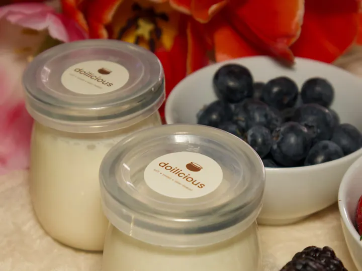 Two jars of Doilicious with blueberries, blackberries and orange tulips