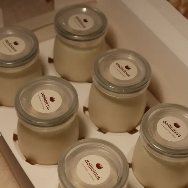 Six jars of Doilicious mishti doi in an open white box