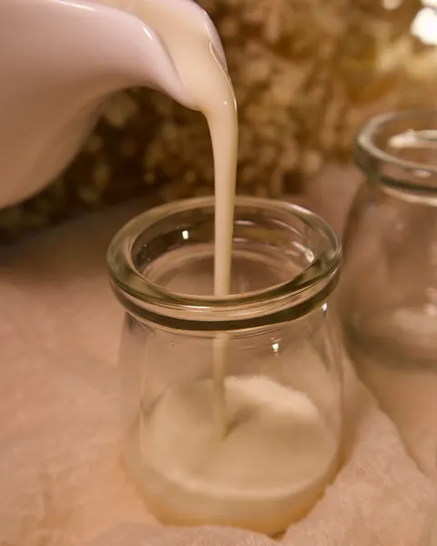 Milk being poured into a glass jar